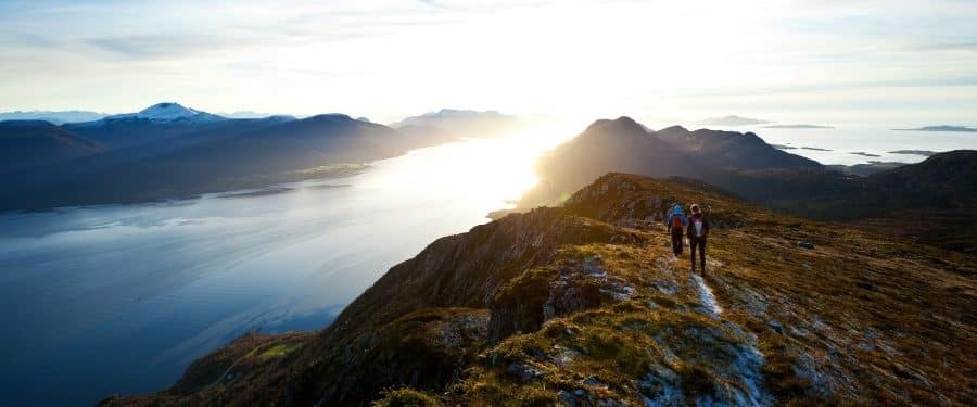 Zwei Personen wandern auf Berggipfel im Sonnenschein - Symbolbild im Beitrag zu Apps für Studenten