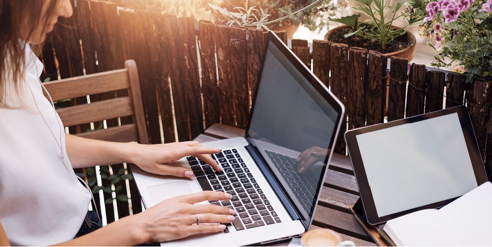 Eine Frau sitzt auf einem Balkon und arbeitet an einem Laptop